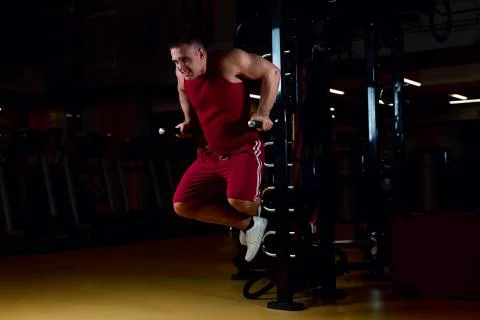 Young athlete doing push ups on parallel bars in gym 写真素材