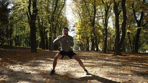 A young athlete is doing warm-up before training in an autumn park Stock Footage 232385573