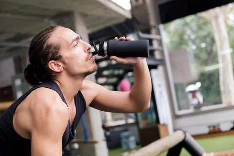 Young athlete drinking water while resting Stock Photos