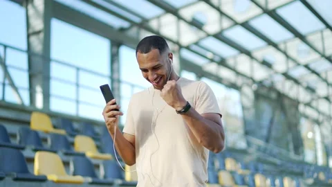 Young athlete in headphones checking workout results on smartphone at urban city Stock Footage 234877051