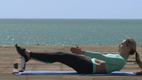 Young athlete lying on the pontoon performs exercises for the abdominals Stock Footage 201543392