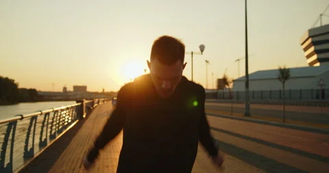 Young athlete making arm circles before training on a city street at sunset Stock Footage 276544804