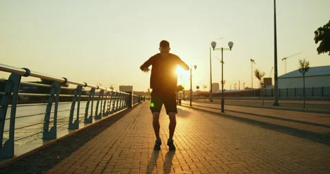 Young athlete making arm circles before training on a city street at sunset Stock Footage 276546151