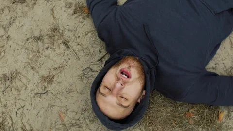 Young athlete man rests on the ground after a sprint run in the forest. Portrait Stock Footage 271129509