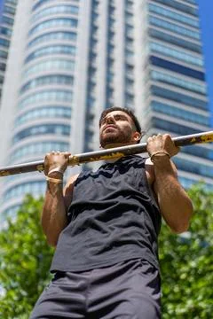 Young athlete performing pull-ups on outdoor gym bars Stock Photos