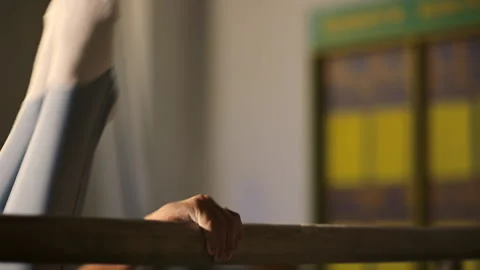 Young athlete performs a gymnastic exercise on the wooden parallel bars beams Stock Footage 205157626