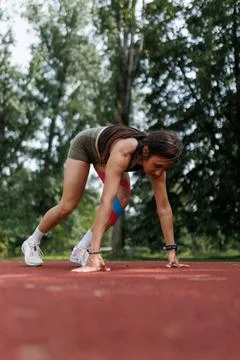 Young athlete preparing for a run on a track in an outdoor park setting Stock Photos