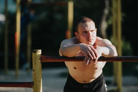 Young athlete resting on parallel bars at outdoor gym on a sunny day Stock-Fotos