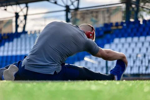 Young athlete runner does a stretch before training, kneads his feet Stock Photos