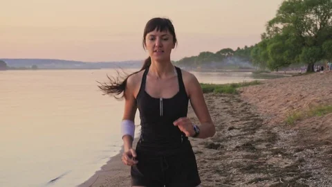 Young athlete runner is runing along the shore of the lake Stock Footage 77696077