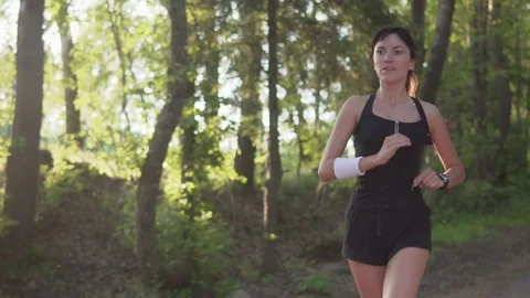 Young athlete runner is runing in the park and looking at the heart rate monitor Stock Footage 77698426