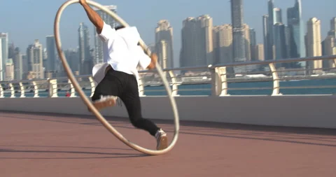 Young athlete is spinning in a wheel, doing gymnastics, Dubai Marina view, 4k Stock Footage 151692147