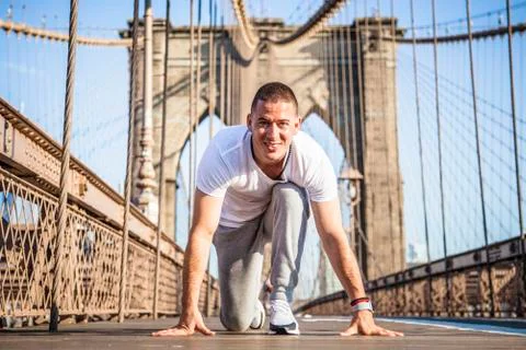 Young athlete sprinter preparing to start a race on Brooklyn Bridge Stock Photos