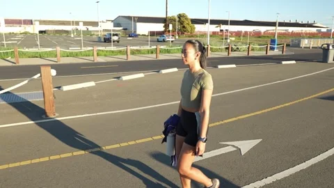 Young athlete walking through a parking lot at sunset 库存影片 330616063