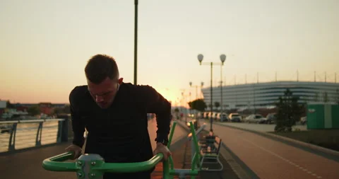 Young athlete working out doing triceps dips on a street sports ground at sunset Stock Footage 276542800