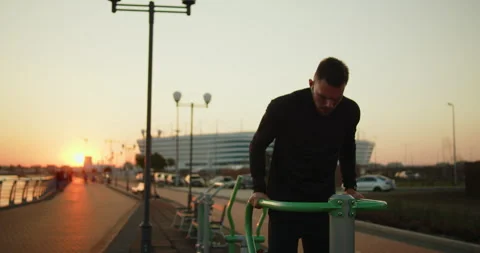 Young athlete working out doing triceps dips on a street sports ground at sunset Stock Footage 276543584
