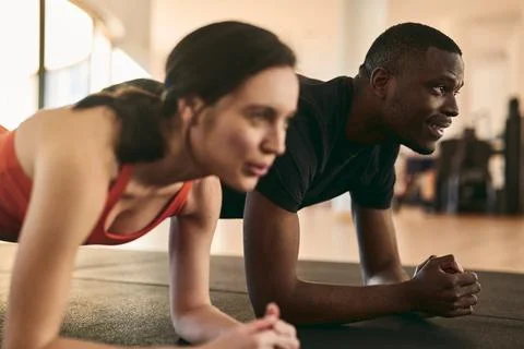 Young athletes doing plank exercise at fitness club Stock Photos