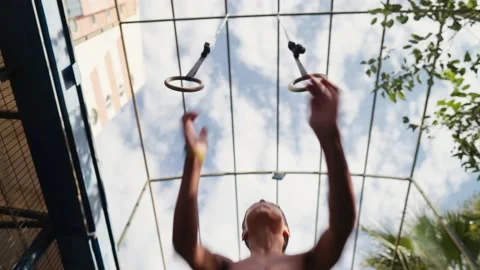 Young athletic boy doing exercise on the gymnastic rings at street workout place Stock Footage 205450715