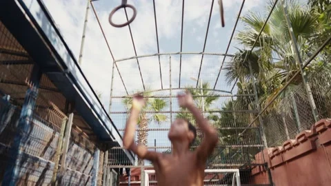 Young athletic boy doing exercise on the gymnastic rings at street workout place Vidéo 206159185