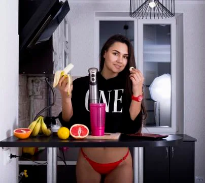 Young athletic girl in the kitchen preparing sports cocktails. sports nutriti Stock Photos