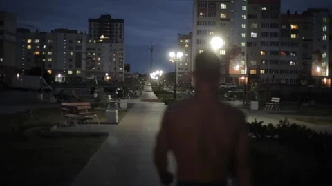 A young athletic guy in blue shorts without t-shirt goes through the city square Stock-Footage 141506129