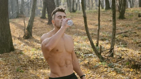 Young Athletic Guy With Naked Torso Stands In The Woods And Drinks Water. Stock Footage 120652014