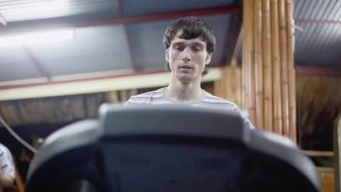 Young athletic handsome man exercising and running on treadmill in sport gym Stock-Footage 84886351