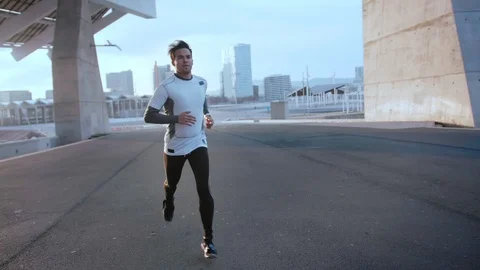 Young athletic Hispanic guy runs outdoor at urban area in evening sunlight near Video stock 105754186