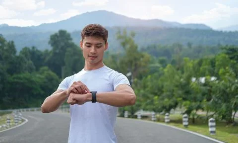 Young athletic man checking heart rate on smartwatch during workout in city.. Stock Photos