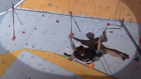 Young athletic man climbs artificial rock wall during the sport competition. Stock Footage 85053258