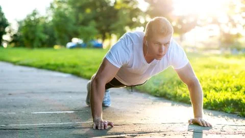 A young athletic man does push-ups. A muscular and strong guy is training. In Stock Photos