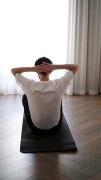 Young athletic man doing ab workout on a fitness mat at home in the early mornin Foto stock