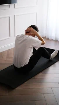 Young athletic man doing ab workout on a fitness mat at home in the early mornin Foto stock