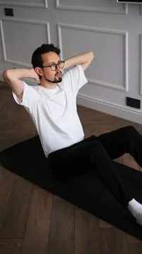 Young athletic man doing ab workout on a fitness mat at home in the early mornin Stock-Fotos