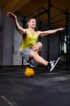 Young athletic man doing exercises in cross fit gym while crouching on one leg Stock Photos