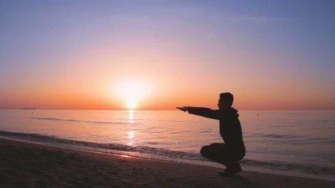 Young athletic man doing gymnastics on the sea early in the morning 動画素材 75317220