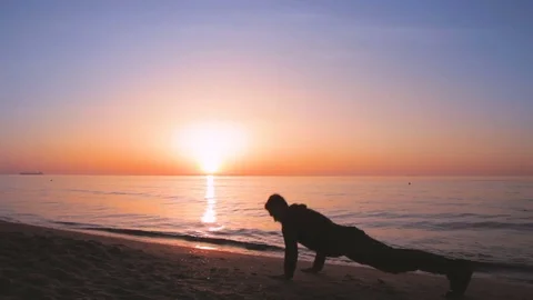 Young athletic man doing gymnastics on the sea early in the morning Stock Footage 75318852