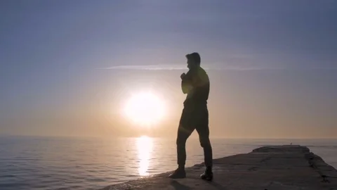 Young athletic man doing gymnastics on the sea early in the morning Stock Footage 75321374