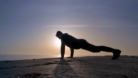 Young athletic man doing gymnastics on the sea early in the morning Stock Footage 75322183
