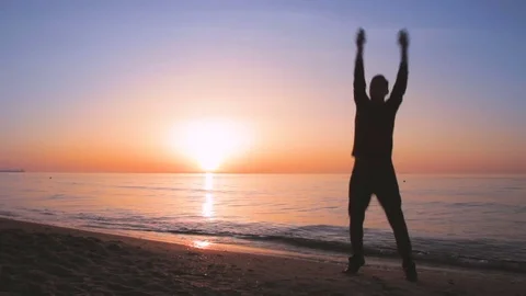 Young athletic man doing gymnastics on the sea early in the morning Stock Footage 75518811