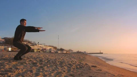 Young athletic man doing gymnastics on the sea early in the morning Video stock 75526606