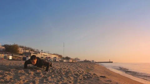 Young athletic man doing gymnastics on the sea early in the morning Vídeos de archivo 75530229