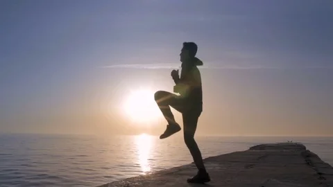 Young athletic man doing gymnastics on the sea early in the morning Stock Footage 75532761