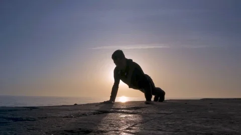 Young athletic man doing gymnastics on the sea early in the morning 動画素材 75533895
