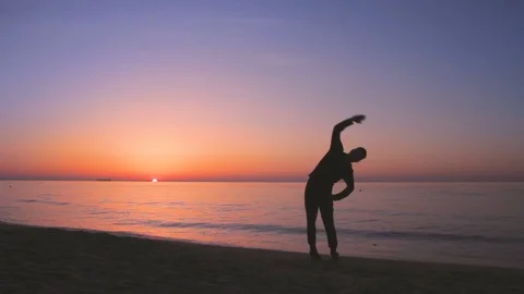 Young athletic man doing gymnastics on the sea early in the morning Vídeos de archivo 75549183