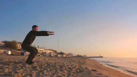 Young athletic man doing gymnastics on the sea early in the morning Stockbeeldmateriaal 75783475