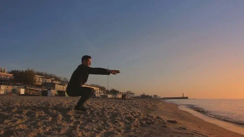 Young athletic man doing gymnastics on the sea early in the morning 스톡 동영상 75970355