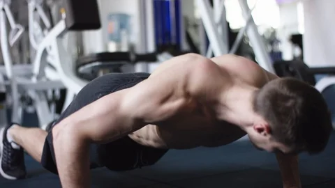 Young athletic man doing push ups in a gym with naked torso Stock Footage 105945543