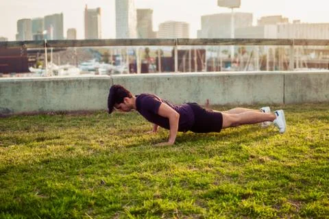Young athletic man doing pushups exercises at park Stock Photos