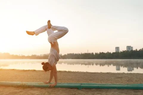 Young athletic man doing yoga poses near the lacke Stock Photos